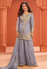 Load image into Gallery viewer, Woman wearing a traditional outfit with intricate designs against an orange architectural background