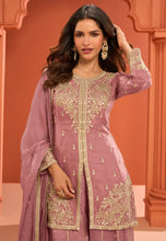 Load image into Gallery viewer, Woman wearing a mauve embroidered traditional outfit against an orange background