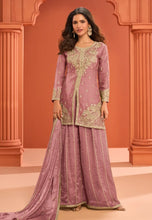 Load image into Gallery viewer, Woman wearing a traditional outfit with intricate embroidery against an orange architectural background