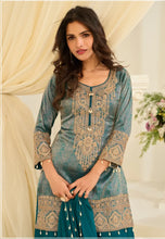 Load image into Gallery viewer, Woman wearing a teal embroidered traditional outfit in a decorated room.