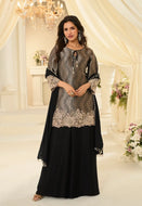 Woman wearing a black and silver traditional outfit in a decorated room.