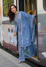 Load image into Gallery viewer, Woman in a blue embroidered outfit stepping out of a tram

