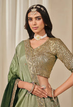 Load image into Gallery viewer, Woman wearing a green lehenga with gold blouse 
