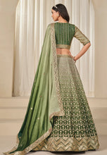 Load image into Gallery viewer, Woman wearing a green and gold traditional lehenga with a matching dupatta.
