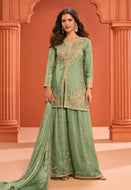 Woman wearing a green embroidered traditional outfit against an orange architectural background