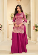Woman wearing a pink traditional outfit with floral patterns in an elegant indoor setting.