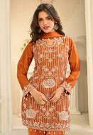 Woman wearing an orange embroidered traditional outfit with a neutral background