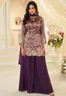 Woman wearing a purple traditional outfit with floral decorations in an elegant indoor setting.